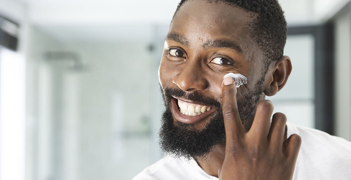 Homem passando creme hidratante antes do creme para tirar manchas no rosto
